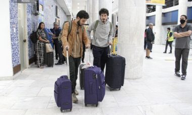 Johnny Massaro desembarca com o namorado em aeroporto do Rio