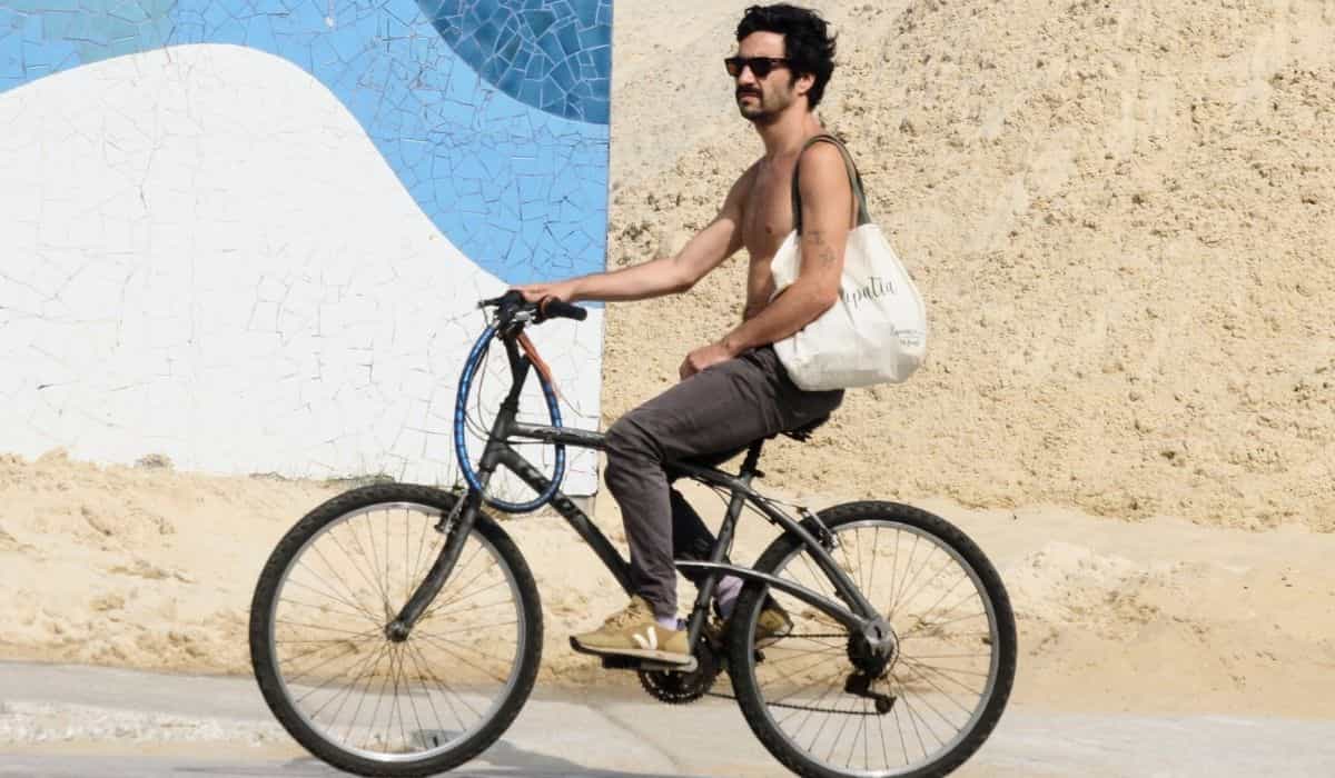 Sem camisa, Caio Blat pedala pela orla da praia no Rio de Janeiro