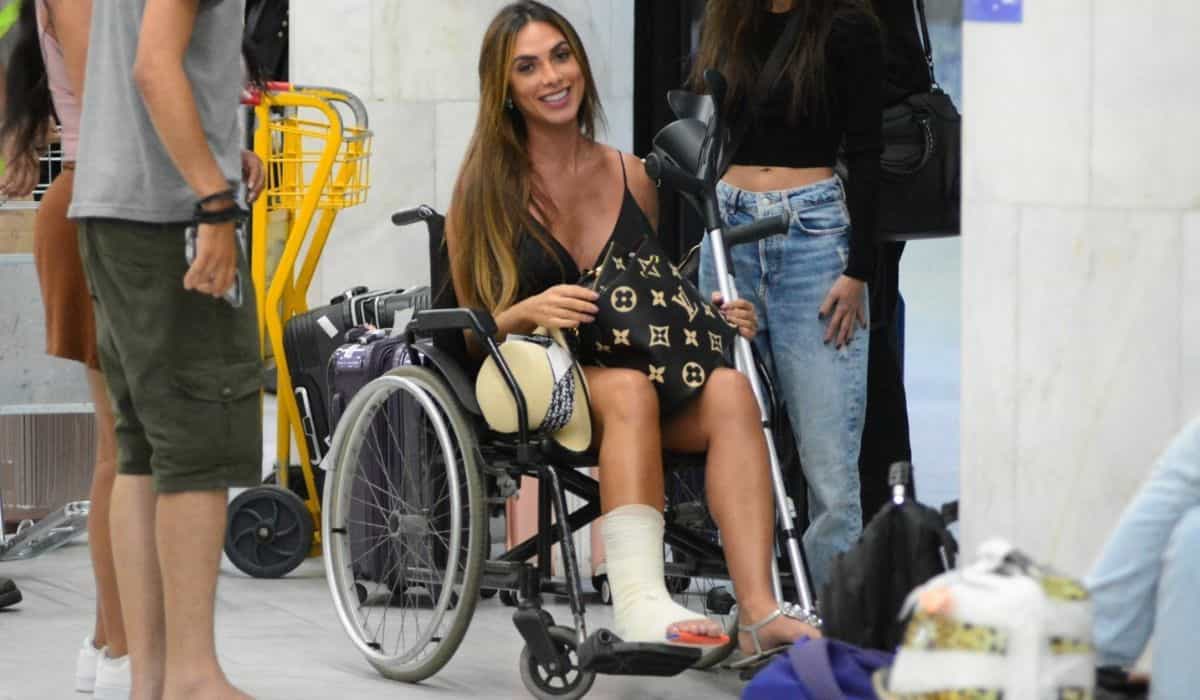 Nicole Bahls é vista de cadeira de rodas após quebrar o tornozelo